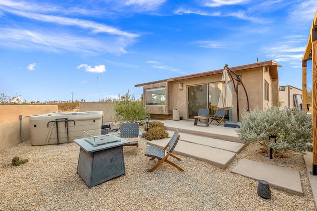 exterior space with a hot tub and a fire pit