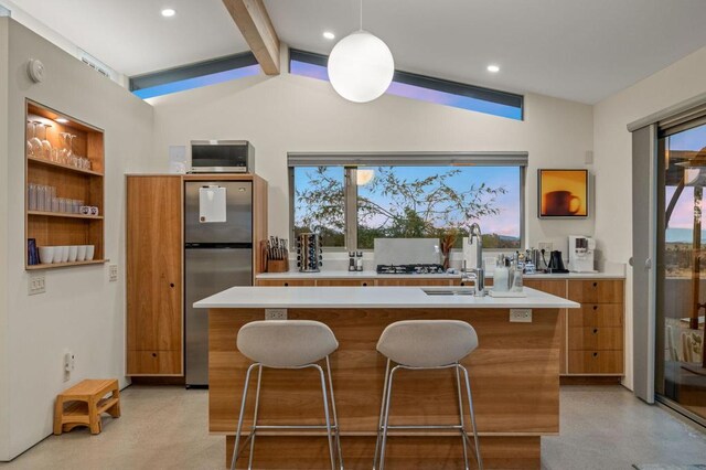 kitchen featuring vaulted ceiling with beams, sink, a center island, and stainless steel refrigerator