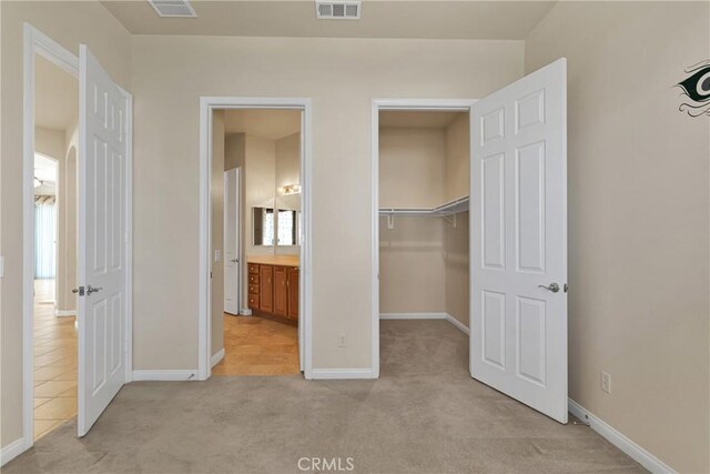 19269 Galloping Hill Rd, Apple Valley, CA 92308 - unfurnished bedroom with light colored carpet, baseboards, a walk in closet, a closet, and ensuite bathroom
