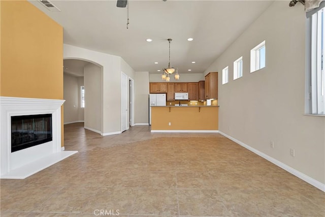 unfurnished living room with light tile patterned floors and ceiling fan with notable chandelier