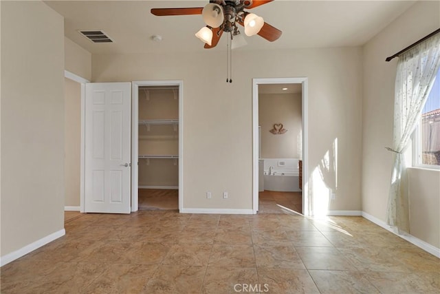 unfurnished bedroom featuring a walk in closet, ensuite bathroom, a closet, ceiling fan, and light tile patterned floors