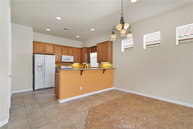 kitchen featuring kitchen peninsula, white appliances, a kitchen breakfast bar, hanging light fixtures, and sink