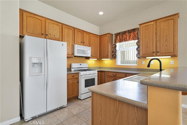 kitchen with sink, white appliances, light tile patterned floors, and kitchen peninsula