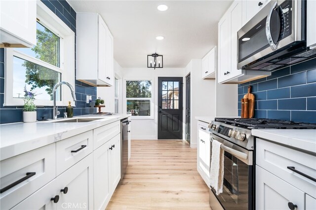 kitchen featuring stainless steel appliances, backsplash, white cabinets, and sink