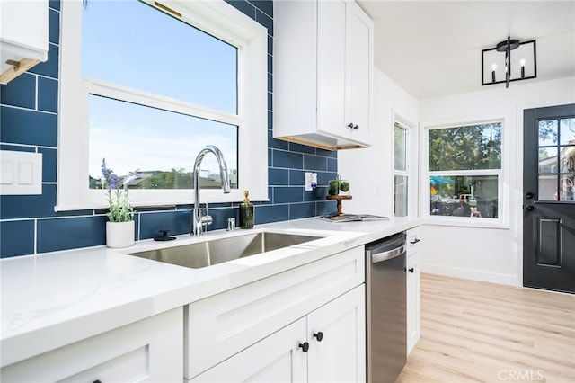 kitchen with white cabinets, a healthy amount of sunlight, decorative backsplash, sink, and light stone counters