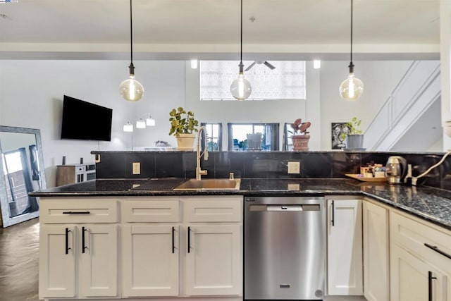 kitchen with dark stone countertops, pendant lighting, a healthy amount of sunlight, and stainless steel dishwasher