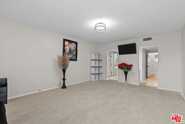 carpeted empty room with a textured ceiling