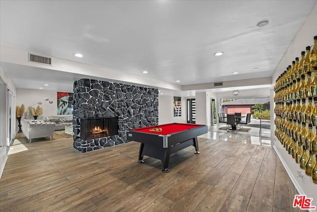 rec room featuring hardwood / wood-style flooring, a stone fireplace, and billiards