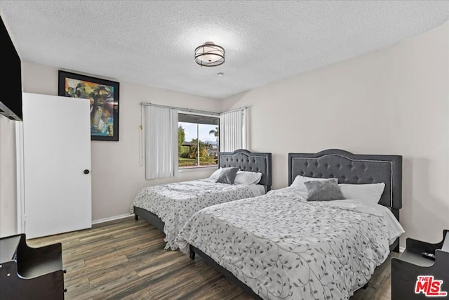 bedroom featuring a textured ceiling and dark hardwood / wood-style floors