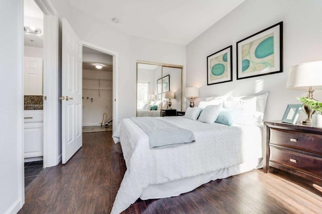 bedroom with dark wood-type flooring, ensuite bathroom, and a closet