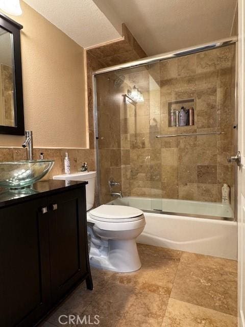 full bathroom with vanity, toilet, and enclosed tub / shower combo