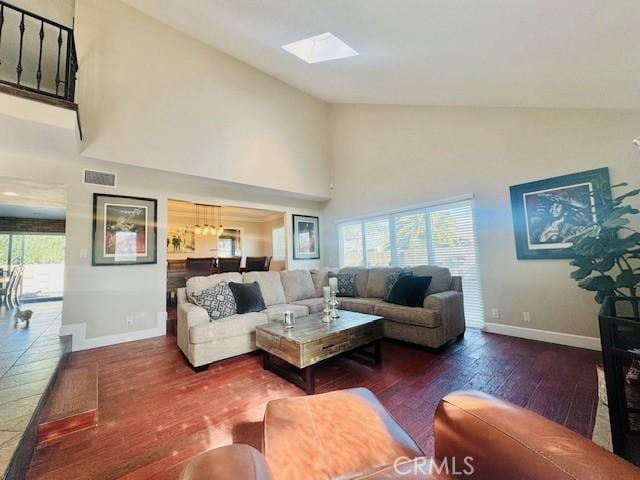 living room with dark hardwood / wood-style flooring, a skylight, and high vaulted ceiling