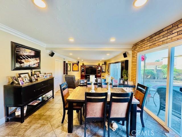 dining space with ornamental molding and brick wall