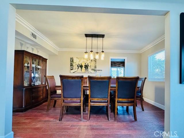 dining area with dark hardwood / wood-style flooring and crown molding