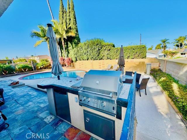 view of patio featuring a grill, a fenced in pool, and exterior kitchen