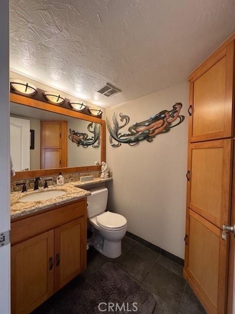 bathroom featuring a textured ceiling, vanity, and toilet