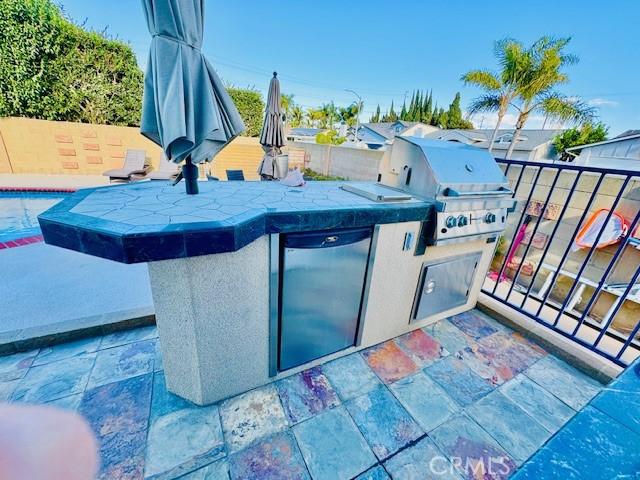 view of patio / terrace featuring a fenced in pool, grilling area, and exterior kitchen