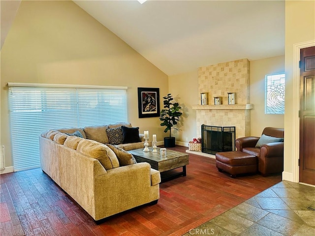 living room featuring dark hardwood / wood-style flooring, high vaulted ceiling, and a tiled fireplace