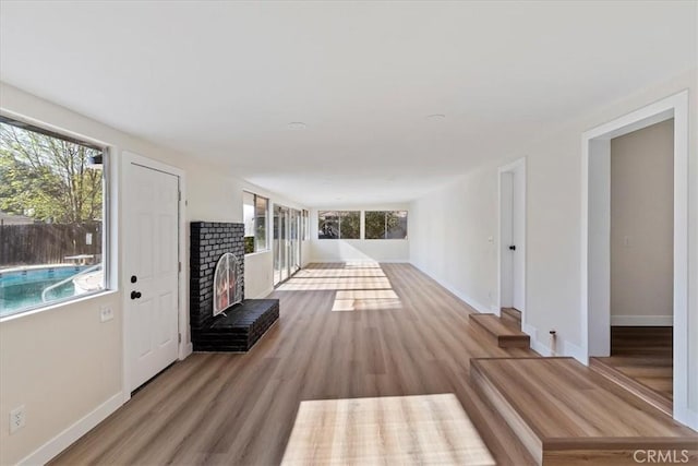 unfurnished living room featuring a brick fireplace, a wealth of natural light, and light hardwood / wood-style flooring