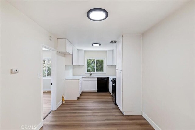 kitchen featuring sink, white cabinetry, black appliances, and hardwood / wood-style floors