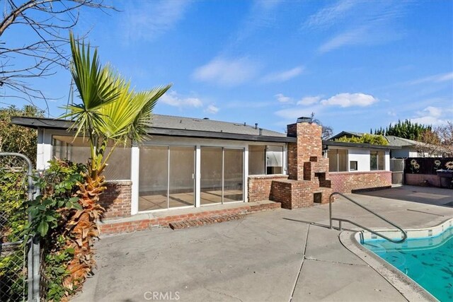 rear view of property featuring a fenced in pool and a patio