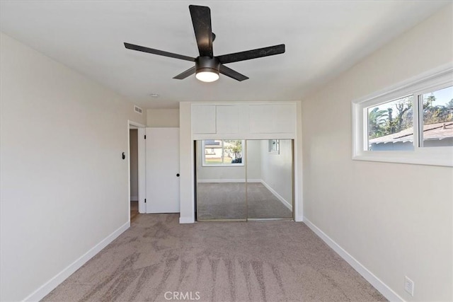 unfurnished bedroom with light carpet, a closet, and ceiling fan