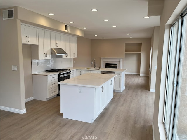 kitchen featuring a center island, light hardwood / wood-style floors, kitchen peninsula, sink, and white cabinets