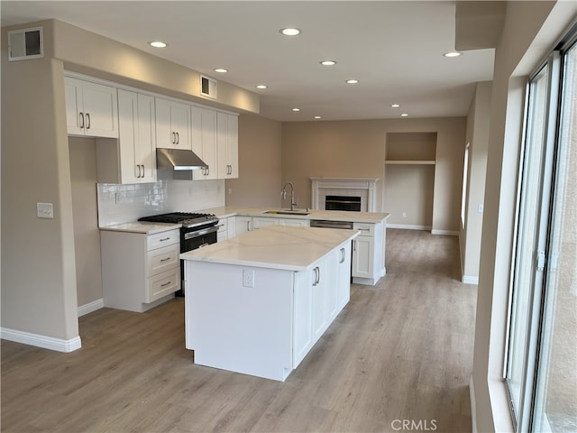 kitchen with a peninsula, a sink, visible vents, and under cabinet range hood