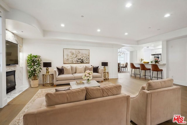 living room with a high end fireplace, a chandelier, and light hardwood / wood-style flooring