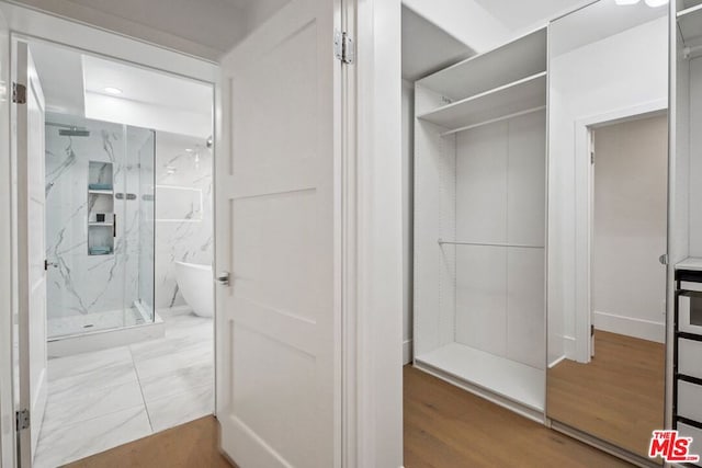 bathroom featuring a shower with shower door and hardwood / wood-style flooring