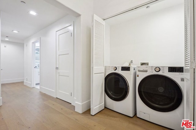 laundry area featuring washing machine and dryer and light hardwood / wood-style flooring