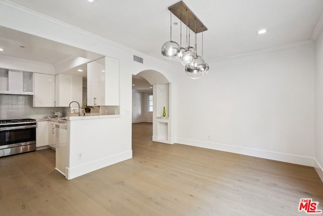 kitchen featuring decorative light fixtures, white cabinetry, stainless steel stove, backsplash, and ornamental molding