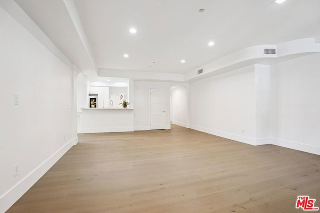 unfurnished living room featuring a tray ceiling and light hardwood / wood-style flooring