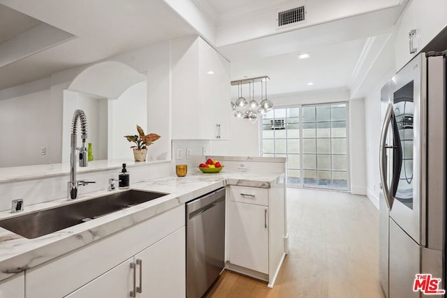 kitchen with kitchen peninsula, appliances with stainless steel finishes, and white cabinetry