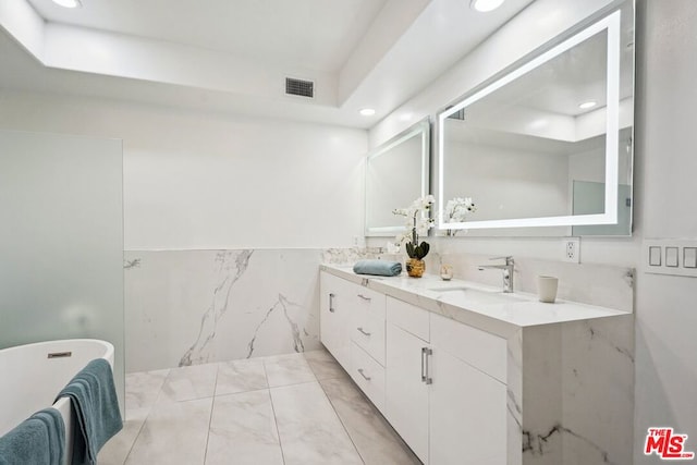 bathroom with a tub to relax in, vanity, and tile walls