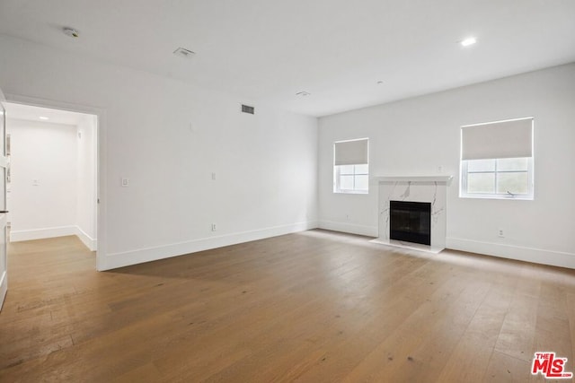 unfurnished living room featuring light wood-type flooring and a fireplace