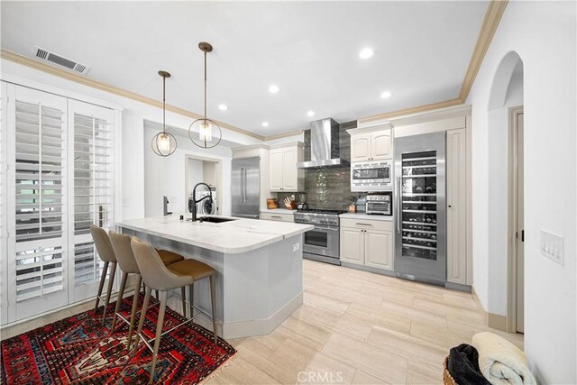 kitchen with wine cooler, pendant lighting, appliances with stainless steel finishes, white cabinets, and wall chimney exhaust hood