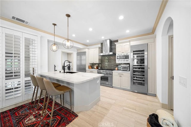 kitchen with appliances with stainless steel finishes, wall chimney exhaust hood, white cabinetry, wine cooler, and hanging light fixtures