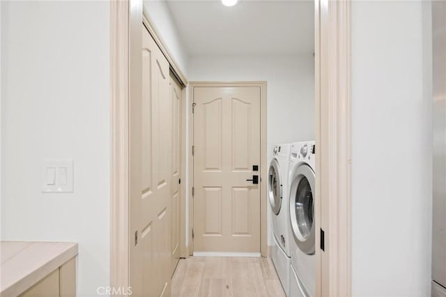 laundry room with separate washer and dryer and light hardwood / wood-style floors