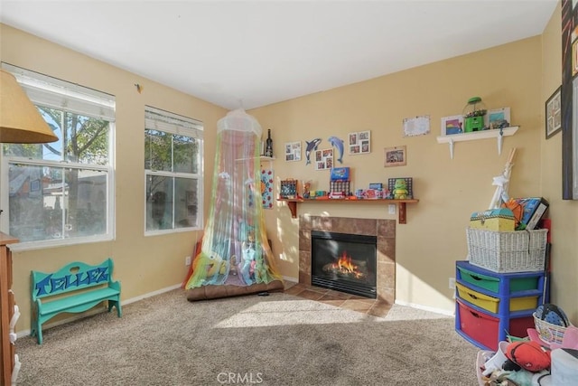 game room with light carpet and a tile fireplace