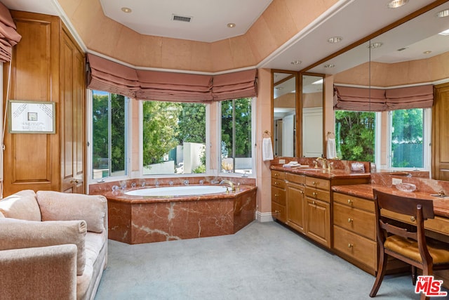 bathroom with tiled bath and vanity