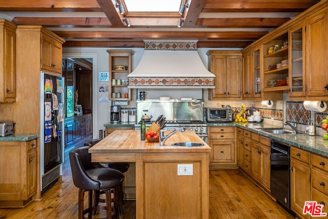 kitchen with light hardwood / wood-style floors, custom range hood, beamed ceiling, and a kitchen island