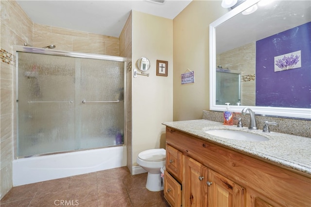 full bathroom featuring toilet, vanity, tile patterned flooring, and enclosed tub / shower combo