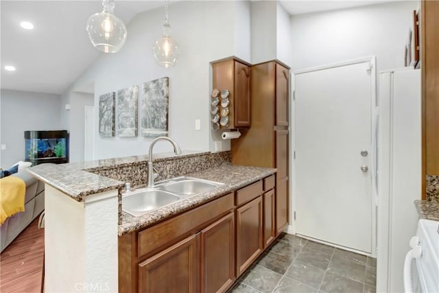 kitchen with lofted ceiling, kitchen peninsula, sink, hanging light fixtures, and range