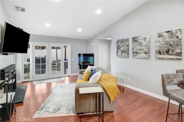 living room with wood-type flooring, vaulted ceiling, french doors, and a fireplace