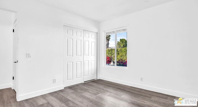 unfurnished bedroom featuring a closet and hardwood / wood-style flooring