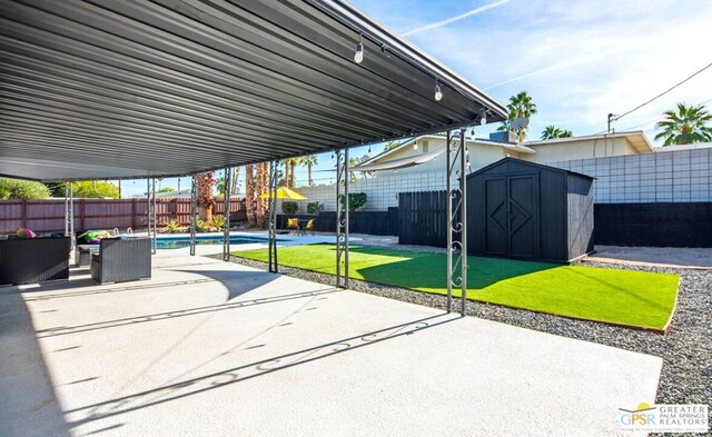 view of patio / terrace featuring a fenced in pool and a storage shed