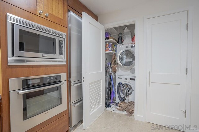 kitchen featuring stacked washer / dryer, wood walls, and stainless steel appliances