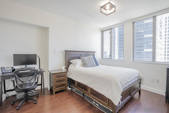 bedroom with multiple windows and dark hardwood / wood-style floors