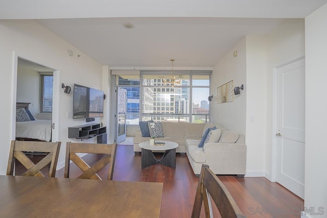 living room featuring dark wood-type flooring, floor to ceiling windows, and a notable chandelier